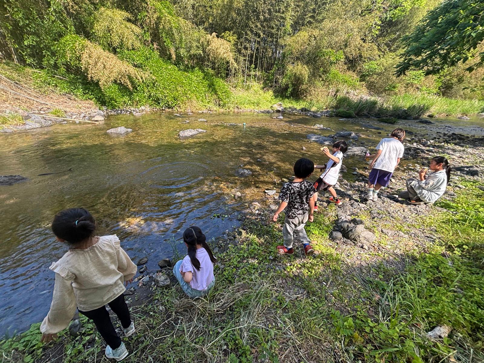 夕方近い川辺。乾いた服で石を投げたり、しゃがんで水面を見ている