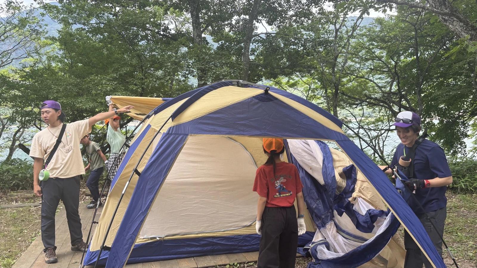 立ち上がったドームテントの布やポールを整えている参加者とスタッフ