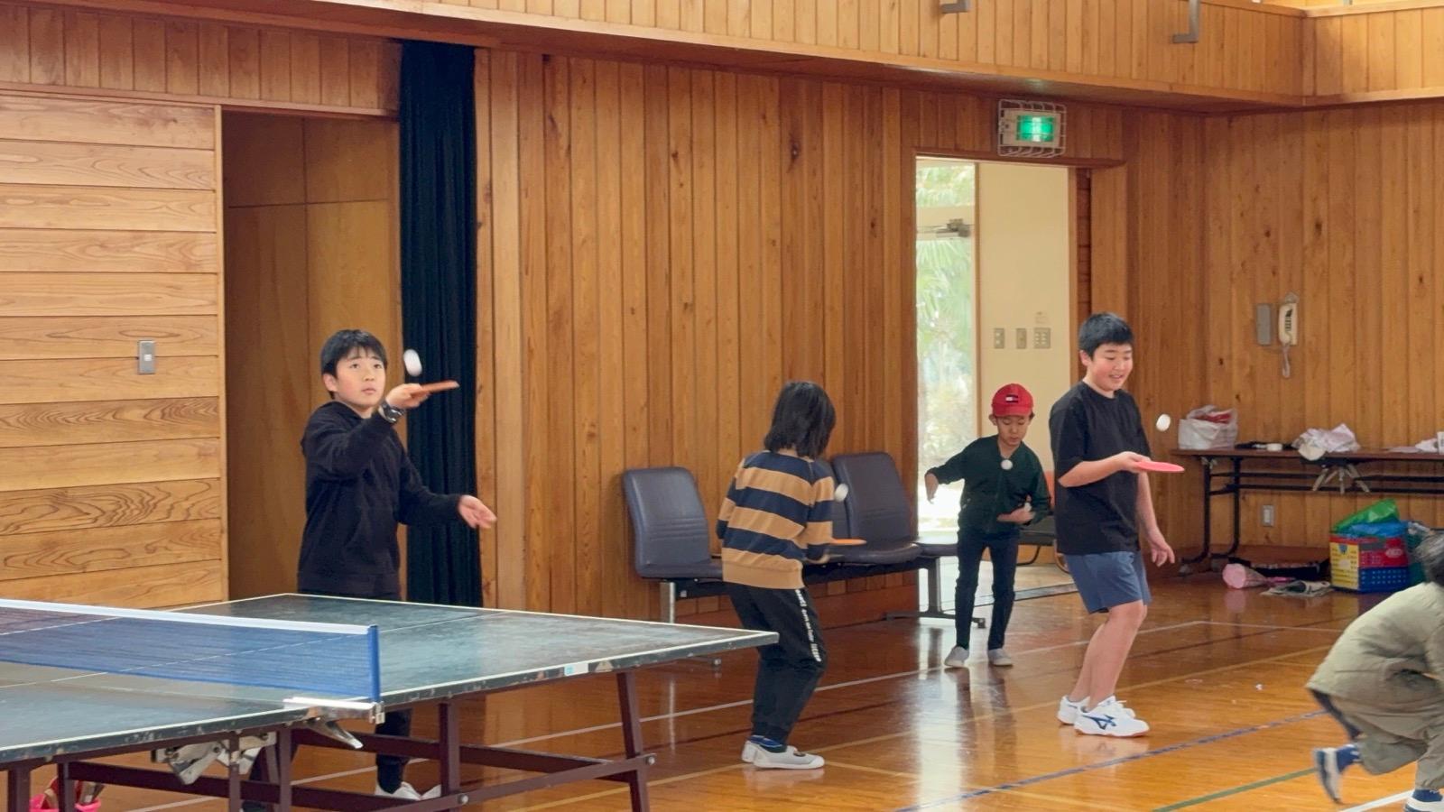 体育館で、子どもたちがピンポン球をラケットの上で弾ませている