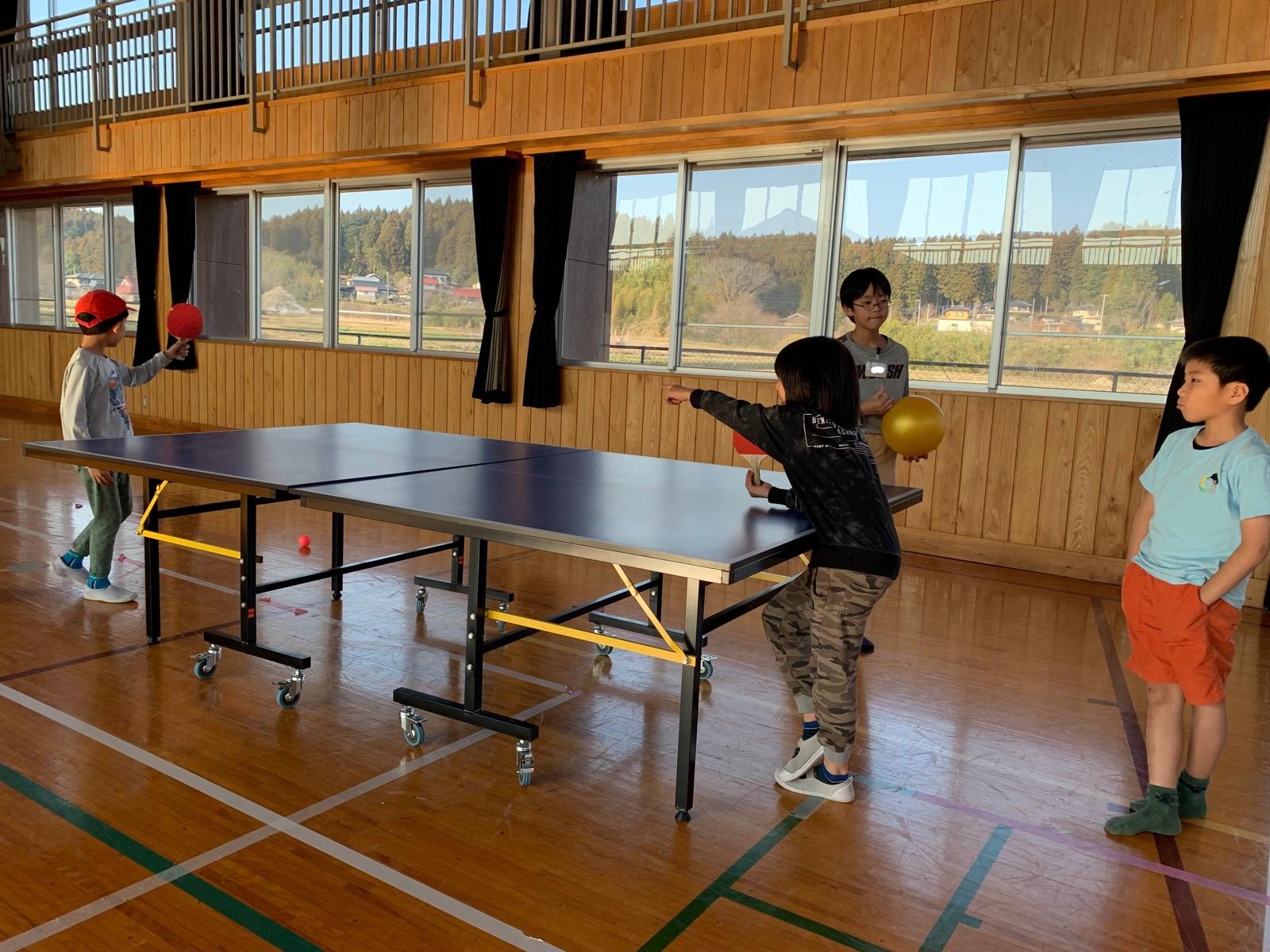 体育館の卓球台で、子どもたちが卓球をしている