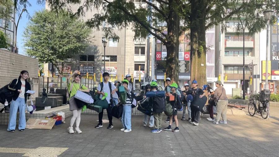 駅前の広場に集まった参加者。大きな荷物と銀マットを抱え、スタッフが色のついたキャップを配っている