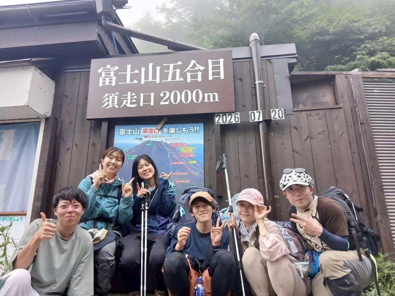 「富士山五合目 須走口 2000m」の看板と「2026 07 20」の日付板の前に並ぶメンバー