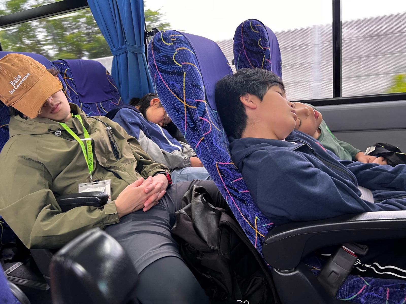 バスの座席で眠り込んでいる子ども。窓際に頭をあずけている