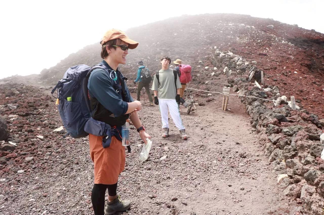 霧のかかった赤茶色の登山道を歩くメンバー