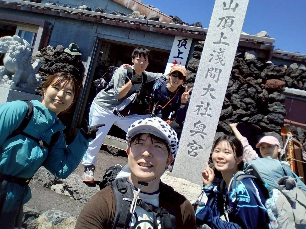 「山頂上浅間大社奥宮」の石柱の前に集まるメンバー