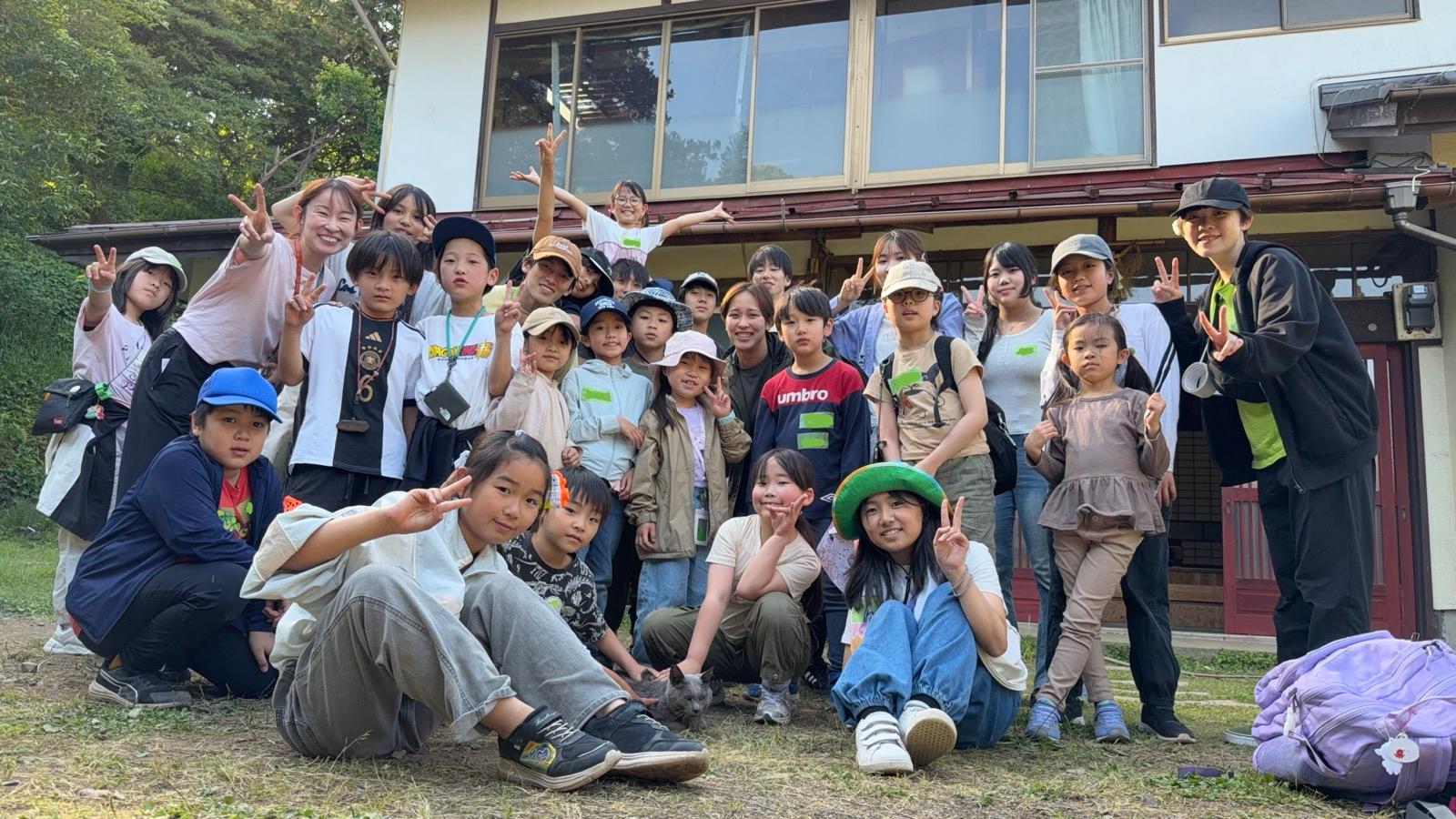 古民家の前で撮った集合写真。子どもたちとリーダーが並び、前列の足元に猫がいる